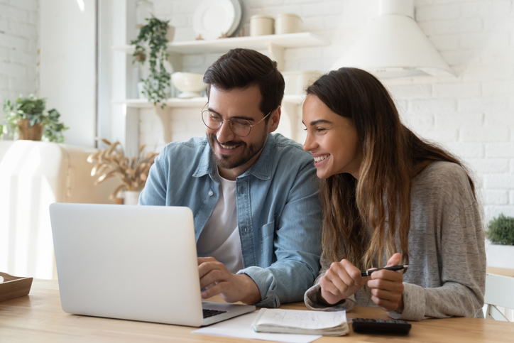 Happy Young Couple Paying Bills Online In Computer App