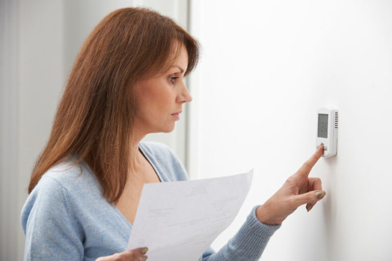 woman adjusting thermostat
